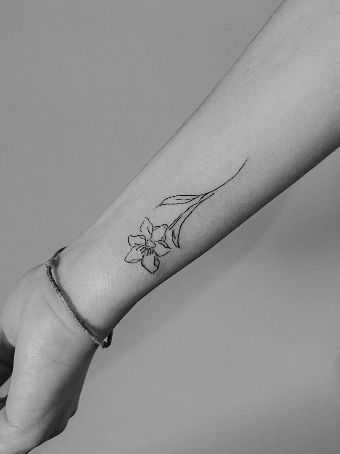 Tatuaje fineline flor en muñeca